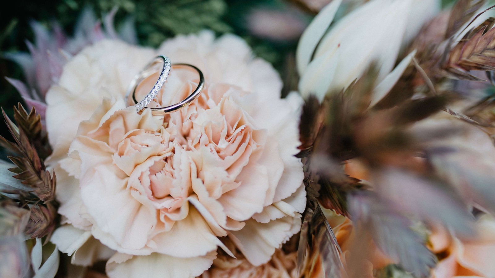 A close up of two wedding rings on a bouquet of flowers (wedding ring, jewellery, engagement, ring, wedding)