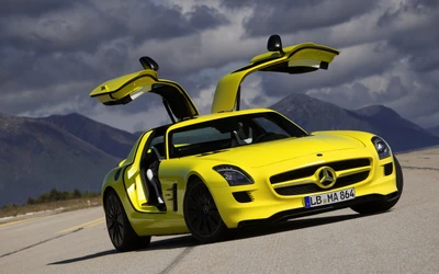 Желтый Mercedes-Benz SLS AMG с дверями типа «крыло чайки», на фоне горного пейзажа.