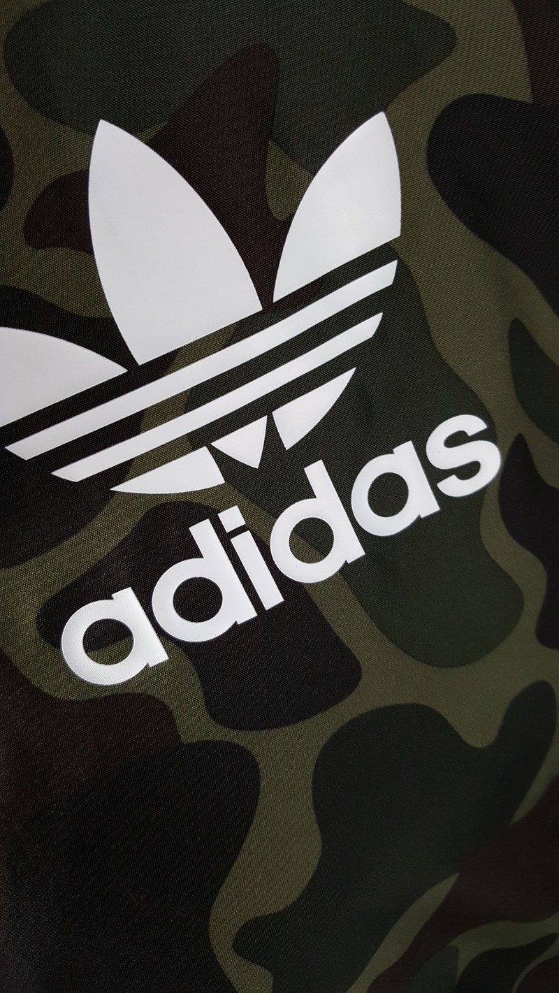 Ближайший план камуфляжной куртки с белым логотипом adidas (реклама, камуфляж, galaxy s8, iphone, айфон 8)