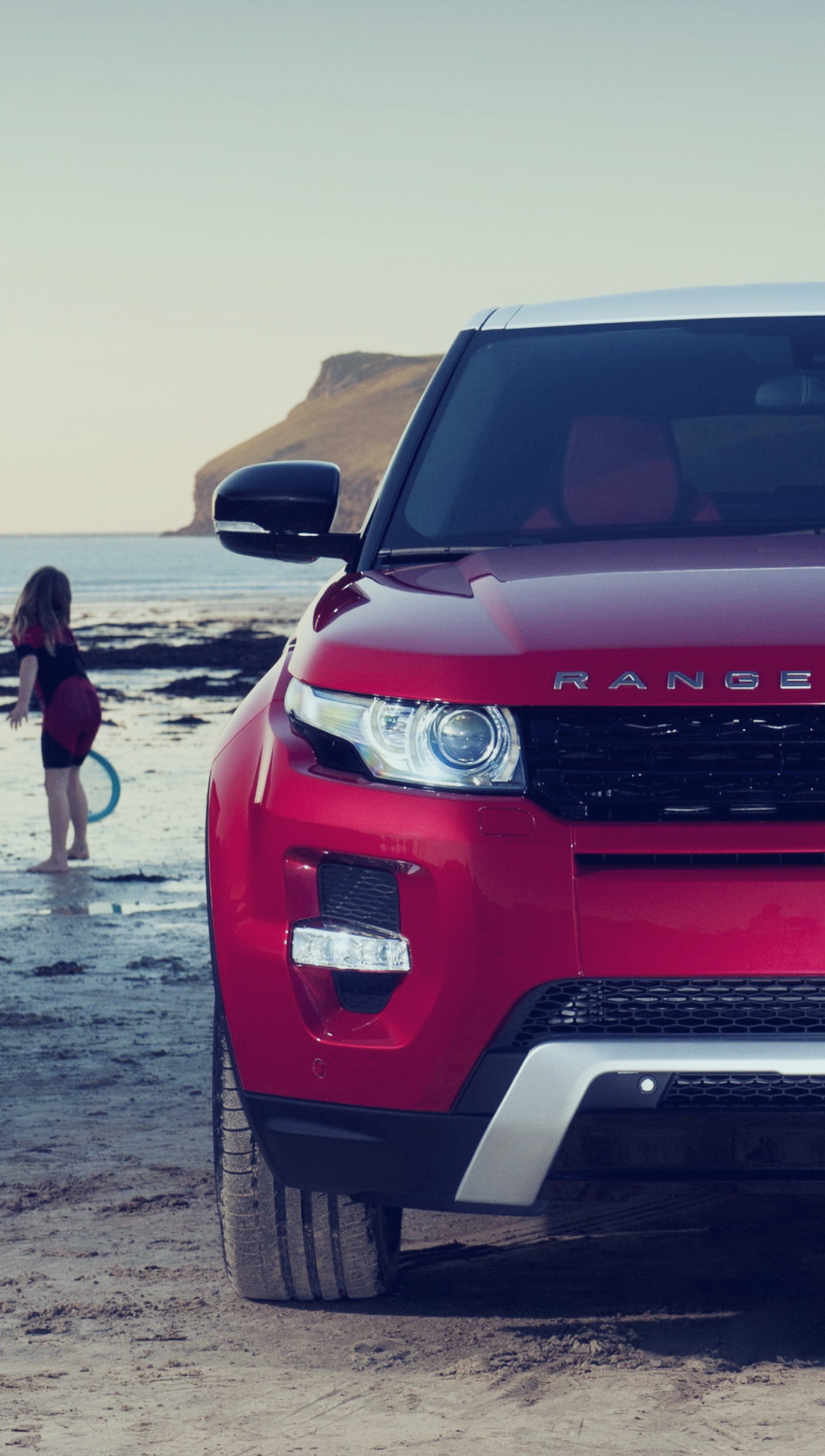 Arafed red car parked on the beach with a woman in the water (car, evoque auto, range rover, range rover evoque)