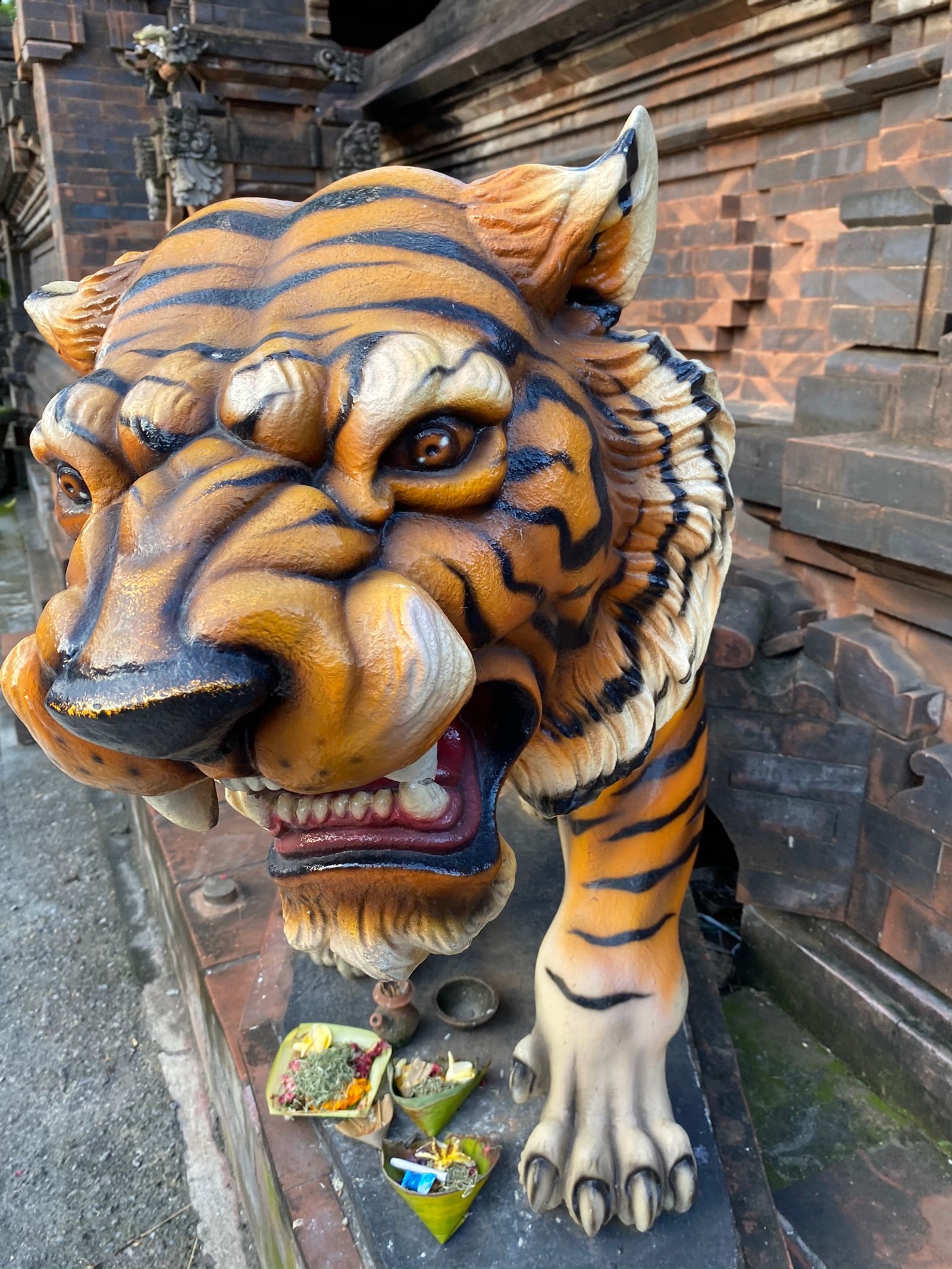 Eine statue eines tigers auf einem vorsprung draußen. (kopf, große katzen, bengalischer tiger, felidae, sibirischer tiger)