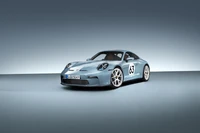 2023 Porsche 911 Heritage Edition in elegantem Blau mit Rennnummer 63, vor einem minimalistischen Hintergrund.