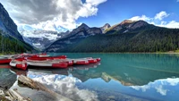 Atemberaubende Reflexion der Gebirgszüge am Lake Louise mit roten Kanus.