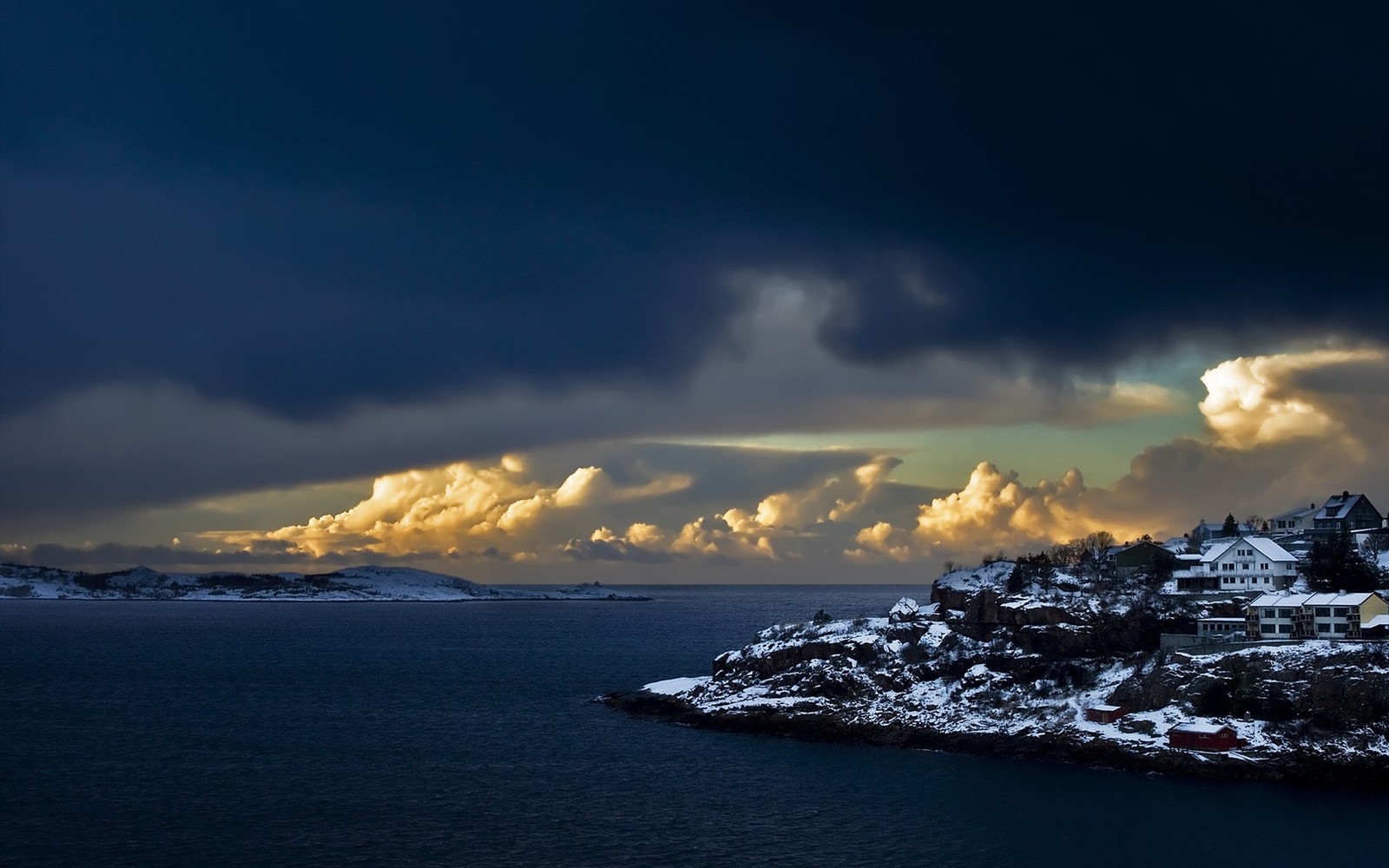 Vue d'une petite ville sur une colline enneigée avec un ciel nuageux (la côte, mer, nuage, horizon, océan)