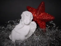 Serene White Angel Figurine Nestled Among Sparkling Tinsel and a Bright Red Star