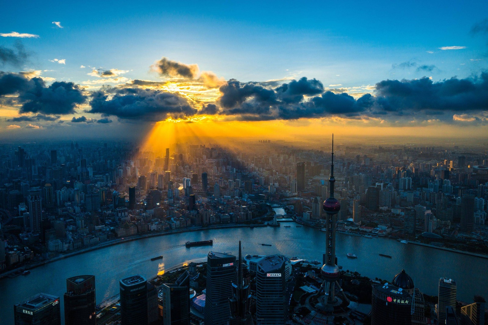 Una vista del sol brillando a través de las nubes sobre una ciudad (shanghai, ciudad, paisaje urbano, metrópolis, panorama)