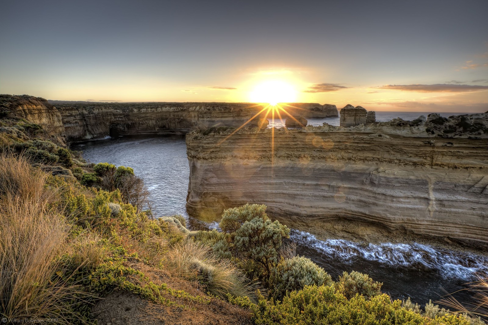 A view of the sun setting over the cliffs of the great ocean road (cliff, sunset, coast, sky, rock)