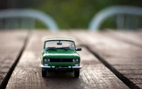 Green Compact Car Model on Wooden Surface