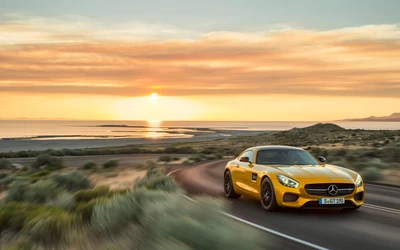 Mercedes-Benz AMG GT jaune sur une route côtière sinueuse au coucher du soleil.