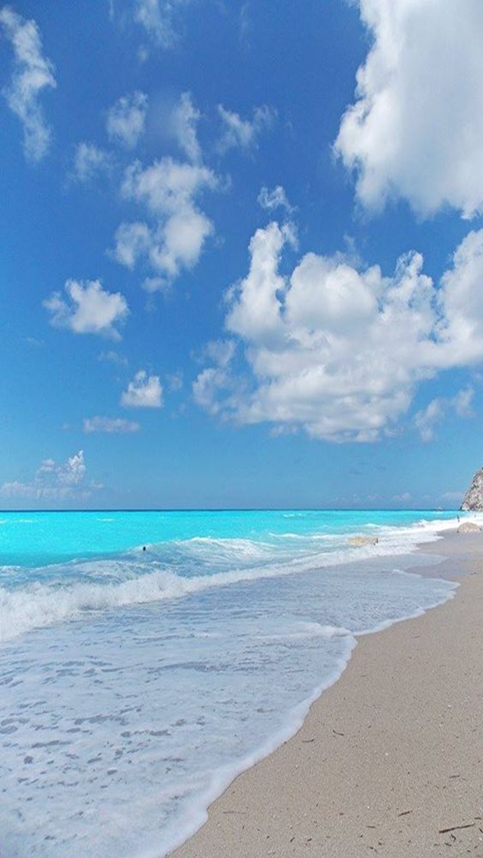 Uma praia com céu azul e nuvens brancas (paisagem, mar)