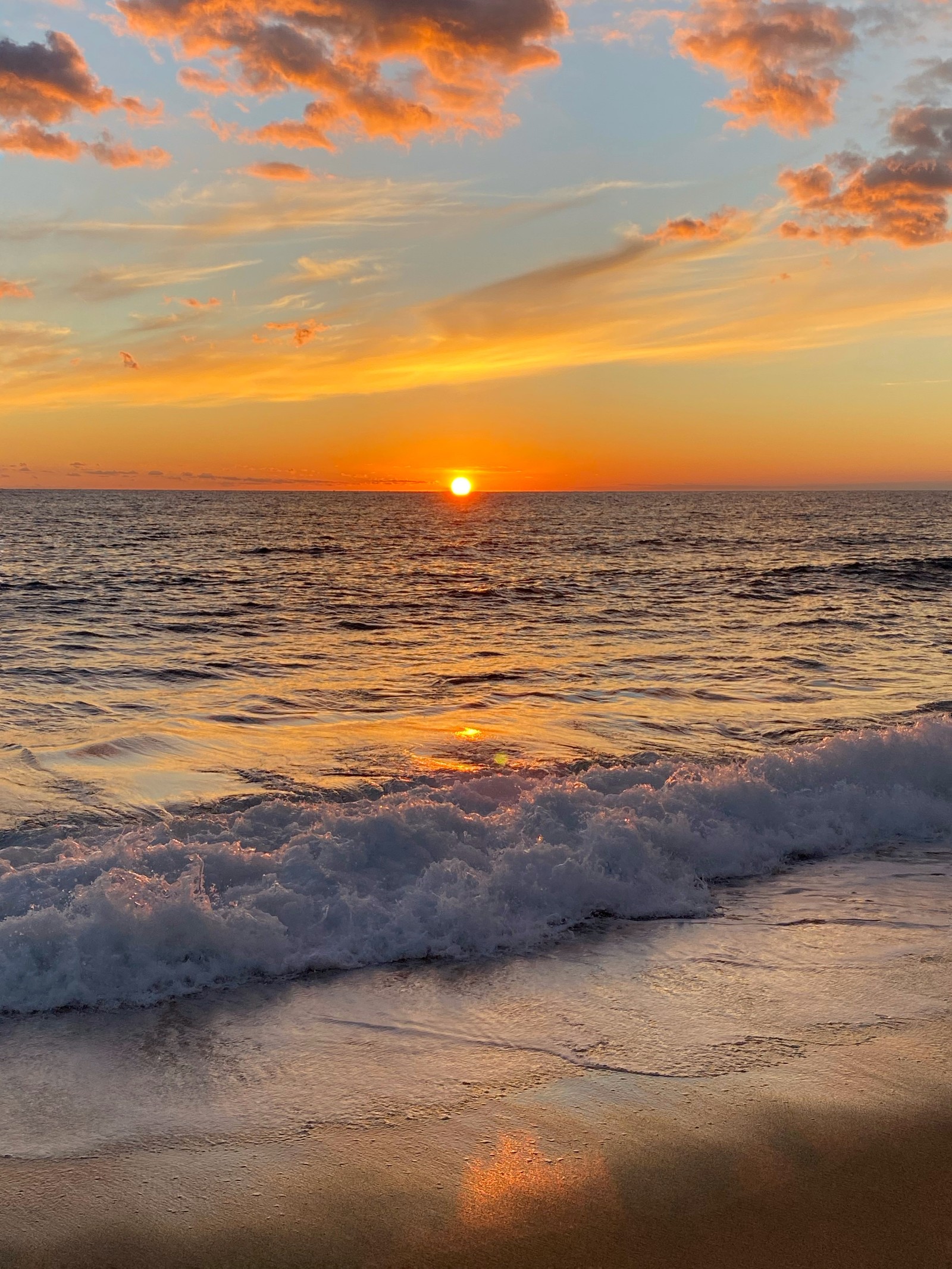 Coucher de soleil sur l'océan avec un surfeur marchant sur la plage (mer, eau, nuage, atmosphère, ressources en eau)