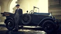 Tommy Shelby s'appuyant contre une voiture vintage dans une scène élégante de "Peaky Blinders