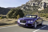 Bentley Continental GTC Convertible violet sur une route de montagne pittoresque