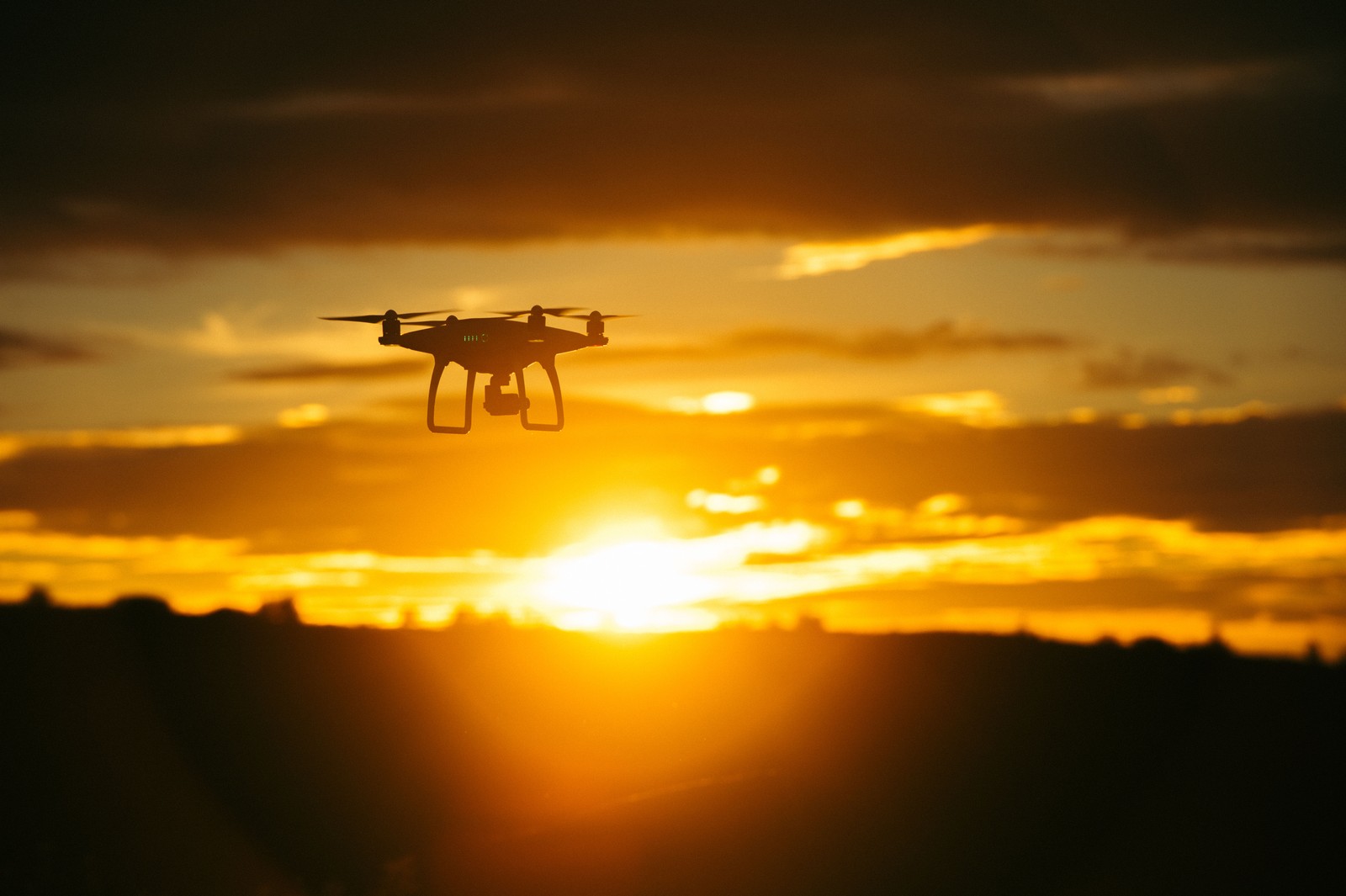 Gros plan sur un petit drone volant dans le ciel (soleil, coucher de soleil, lever de soleil, nuage, matin)