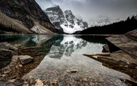 Reflejos brumosos de montañas cubiertas de nieve en el lago Moraine, Canadá