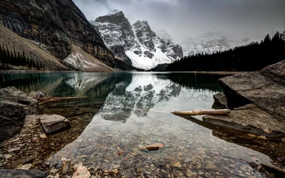 Nebelige Reflexionen von schneebedeckten Bergen am Moraine Lake, Kanada