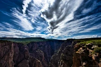 Dramatic clouds loom over a rugged canyon landscape, showcasing the grandeur of nature in a national park setting.