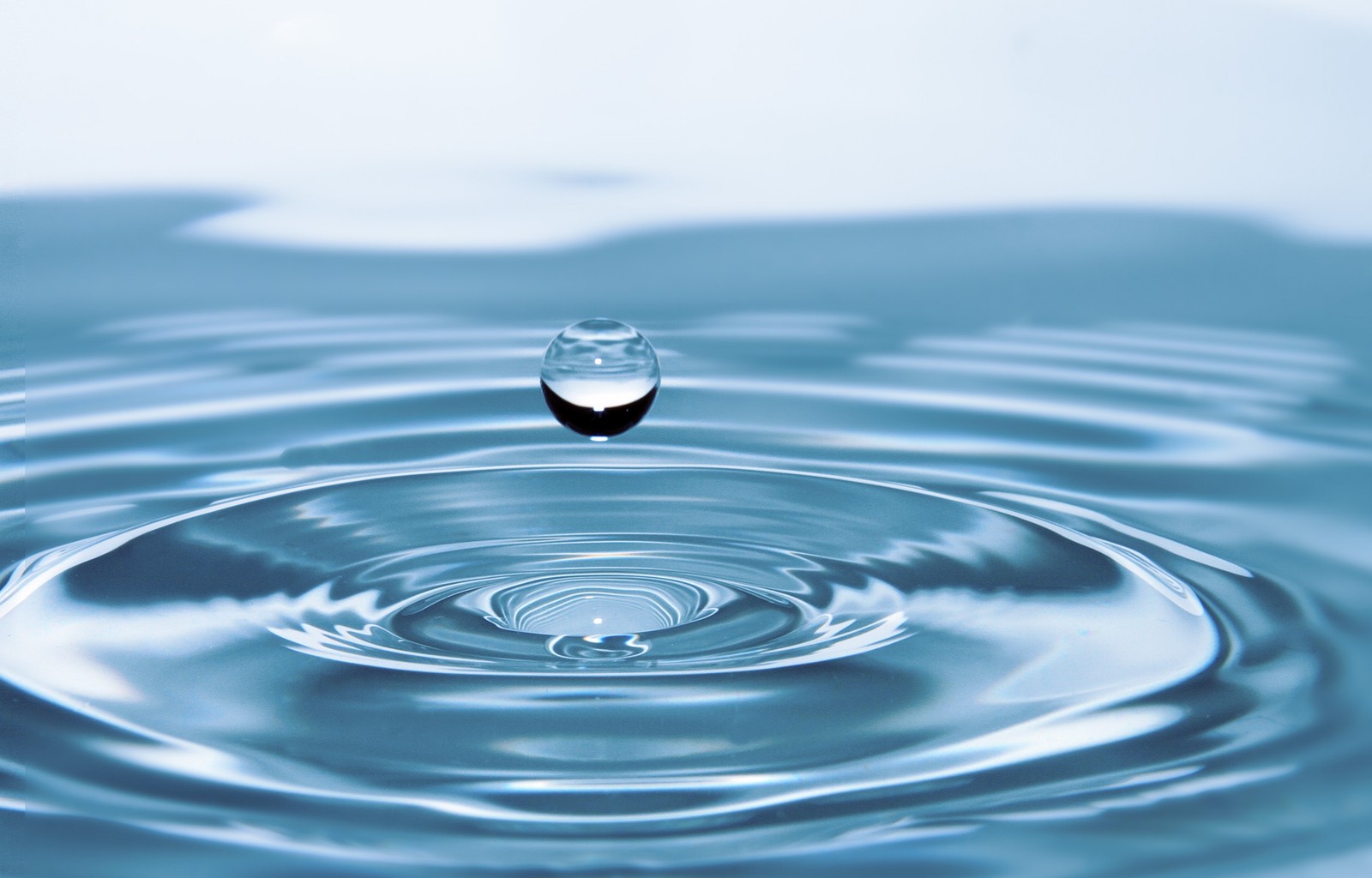 A close up of a water drop in a pool of water (water, drinking water, liquid, fluid, blue)