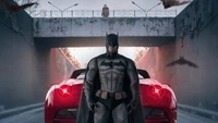 Batman steht stark mit ikonischem rotem Auto in städtischer Landschaft