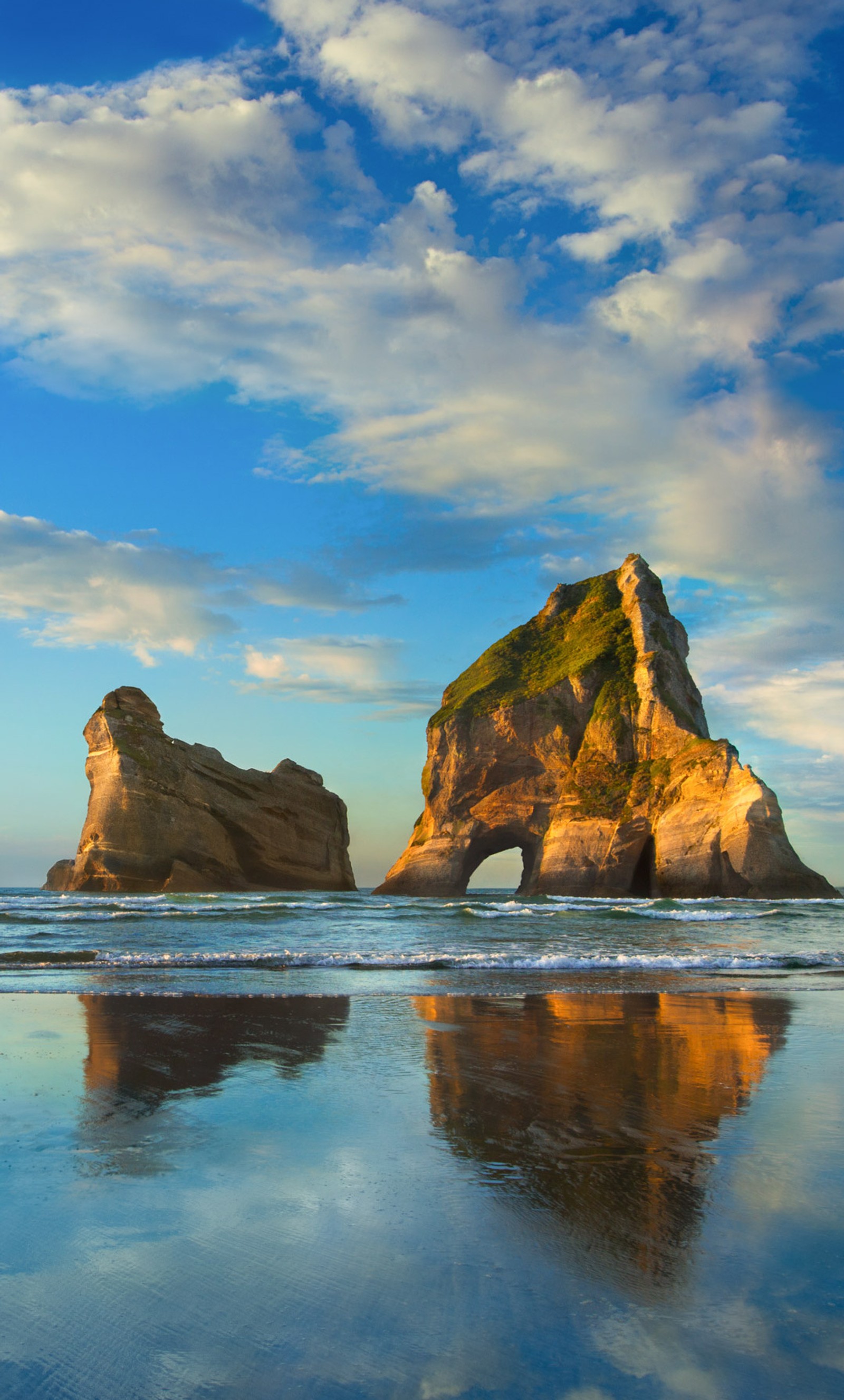 Il y a une grande formation rocheuse sur la plage avec un reflet dans l'eau (nuages, paysage, plage, win10)