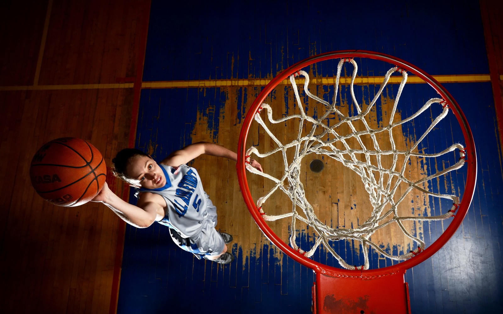 Uma foto aérea de um menino jogando basquete em uma quadra (basquetebol, jogo de bola, iluminação, recreação ao ar livre, snowboard)