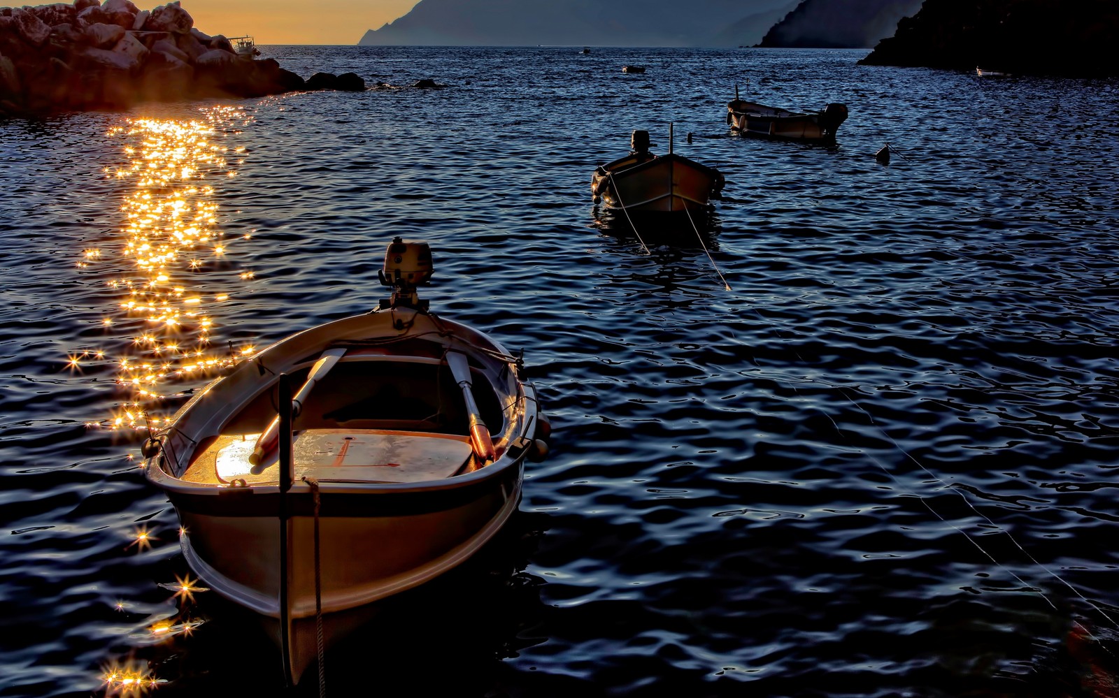 Barcos flutuando na água ao pôr do sol perto de uma costa rochosa (barco, água, embarcação, luz, lago)