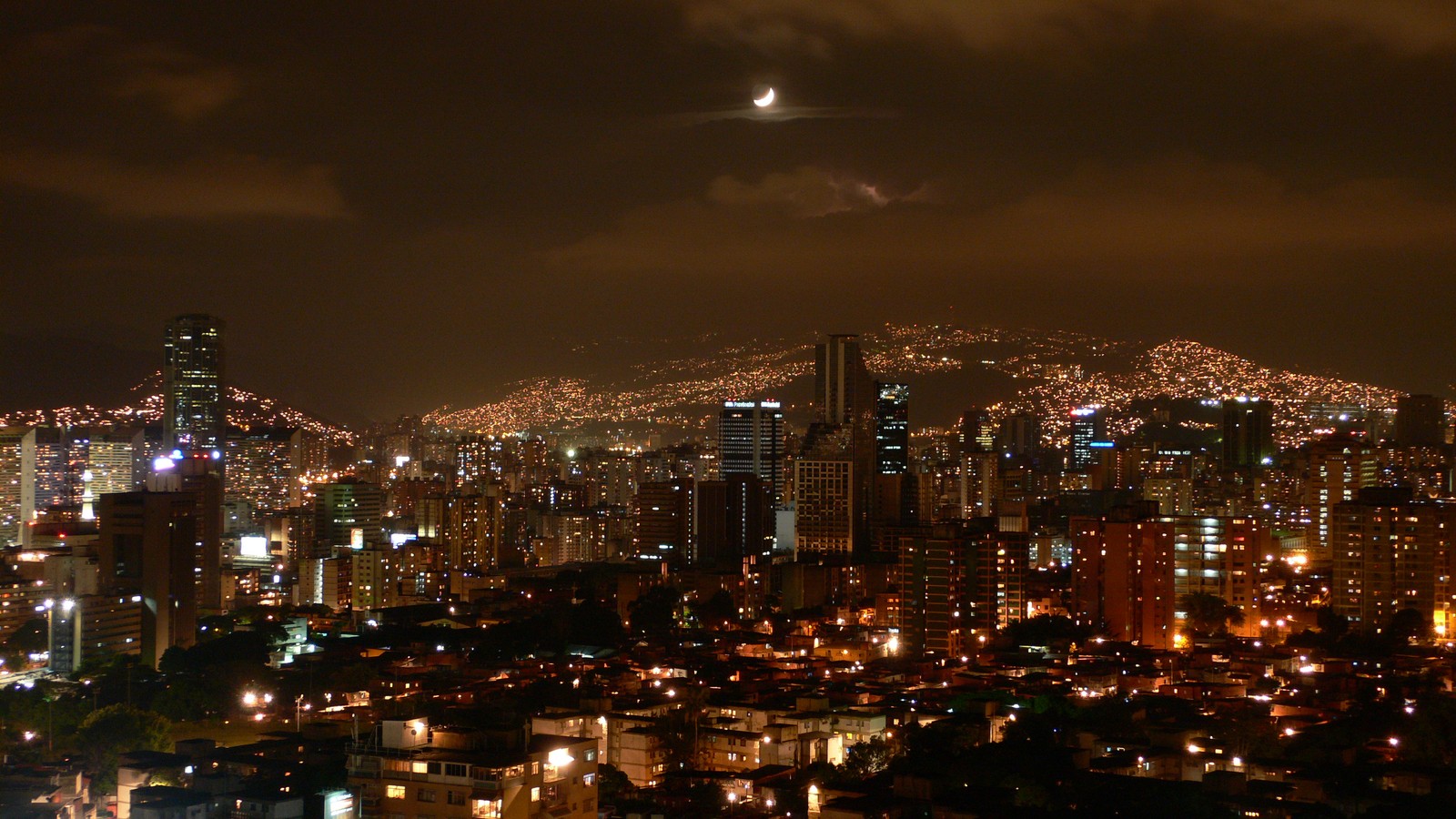 Uma vista árabe de uma cidade à noite com uma lua no céu. (cidade, paisagem urbana, noite, metrópole, área urbana)