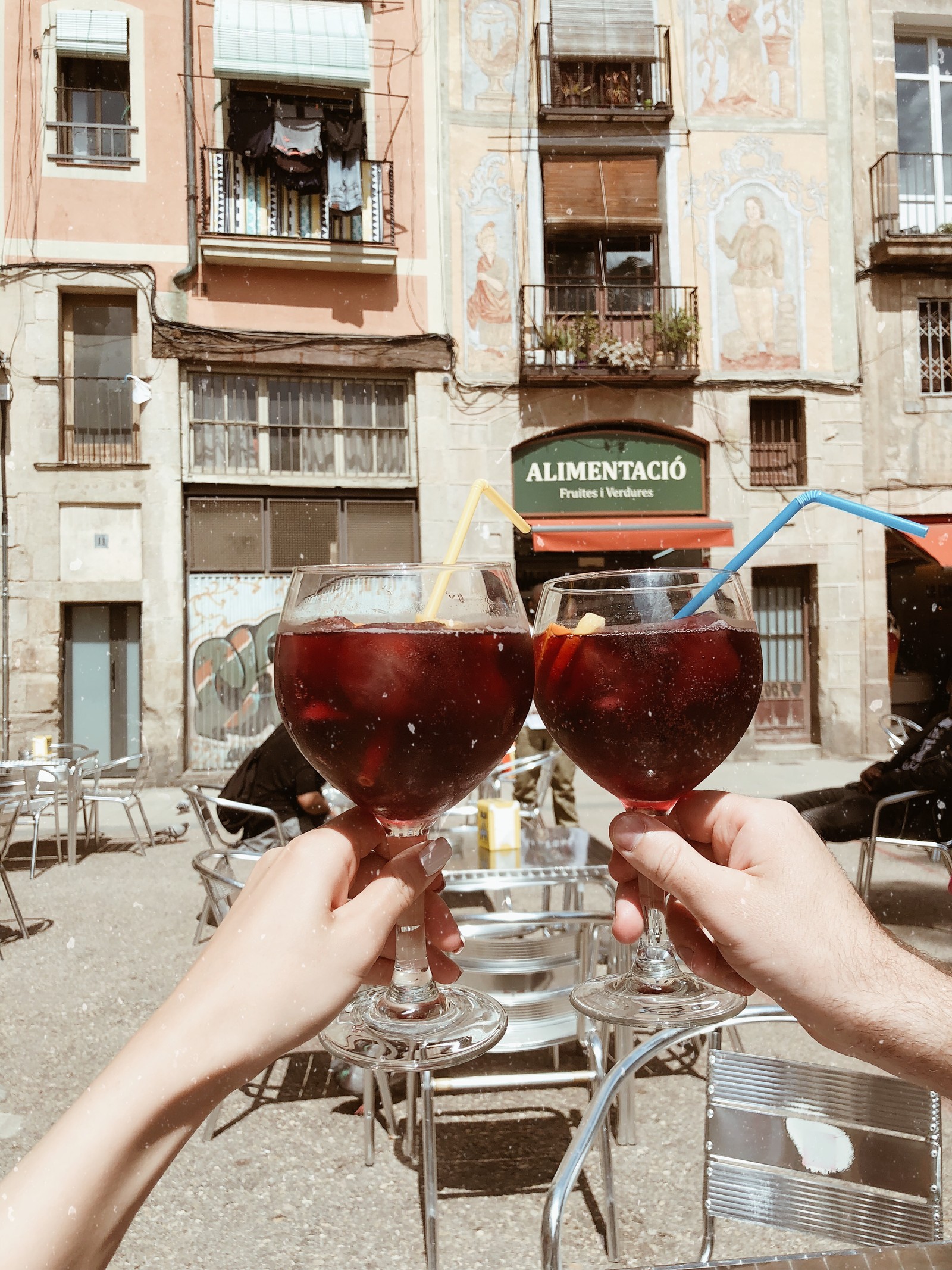 Alguien sosteniendo dos copas de vino frente a un edificio (copa de vino, vino, vino tinto, cristalería, vidrio)