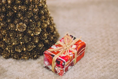 Cadeau de Noël joliment emballé près d'un arbre décoratif