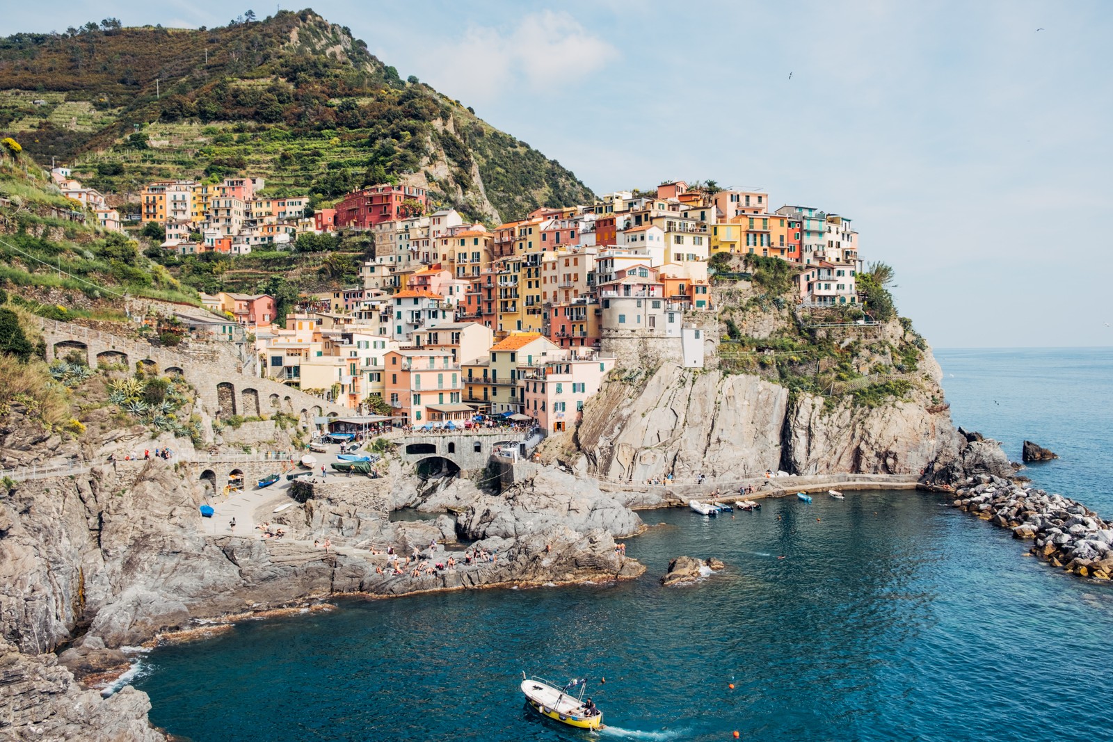 Arafed boat in the water near a small town on a cliff (manarola, vernazza, portofino, travel, water)