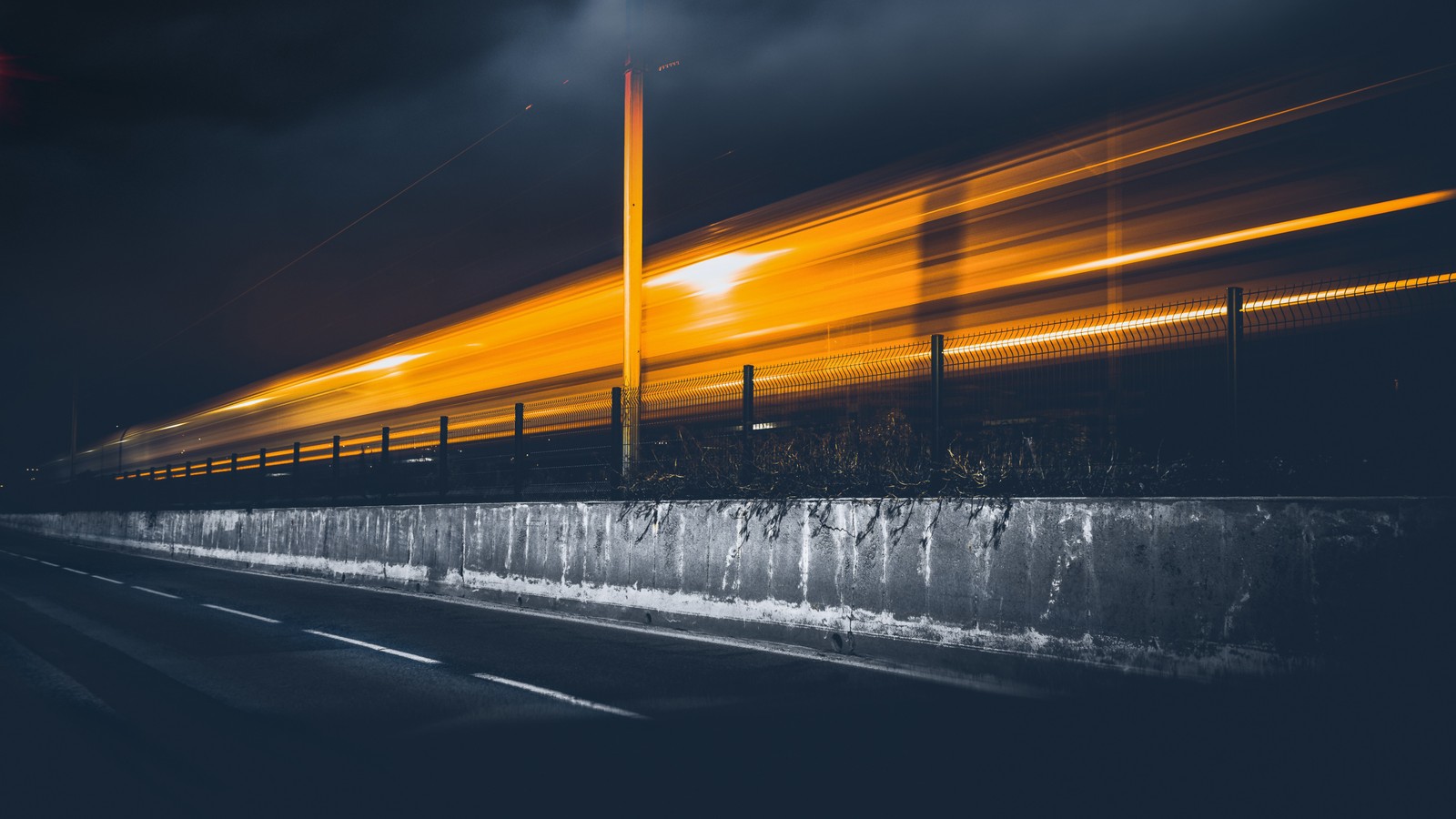 Uma imagem árabe de um trem passando por uma ponte à noite (exposição, nuvem, iluminação automotiva, superfície da estrada, asfalto)