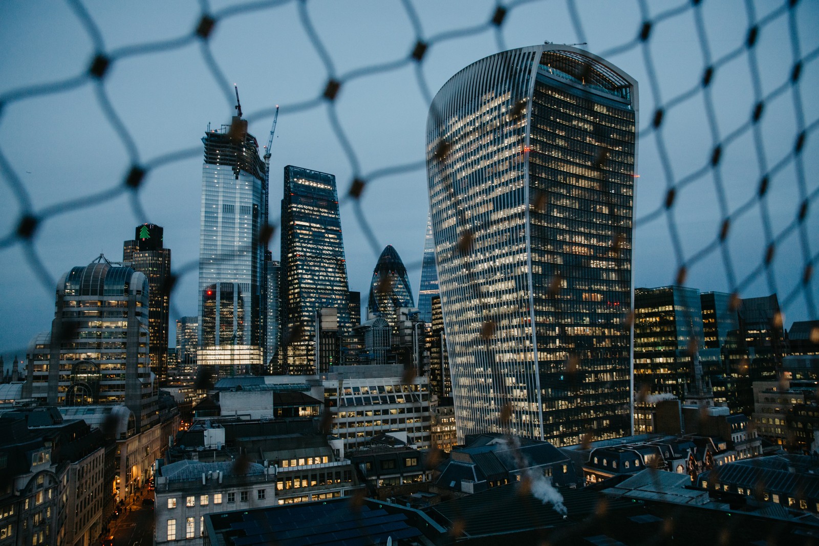 Uma vista árabe do horizonte da cidade através de uma cerca à noite (paisagem urbana, linha do horizonte, metrópole, the shard, arranha céus)