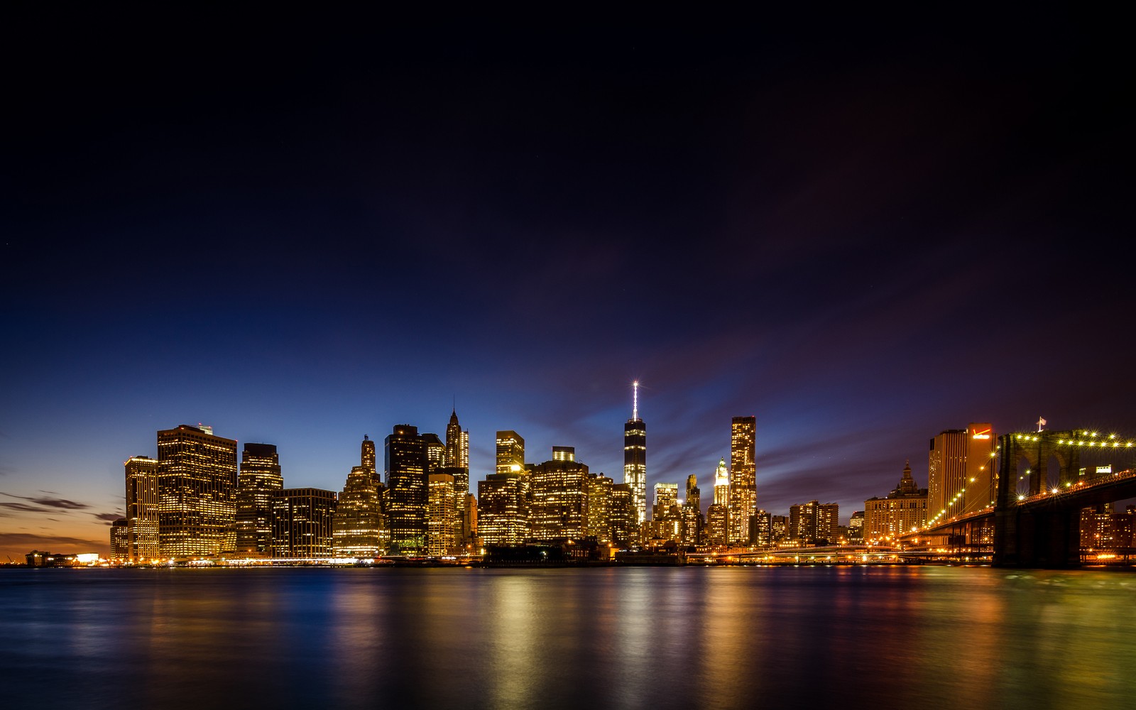 Blick auf die skyline der stadt vom wasser aus bei nacht (brooklyn brücke, nacht, stadt, stadtbild, skyline)