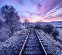 Vías de tren cubiertas de escarcha bajo un vibrante amanecer en Belgrado.