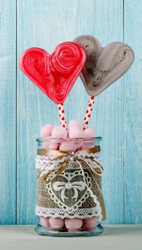 Colorful heart-shaped lollipops in a decorative jar filled with pink sweets.