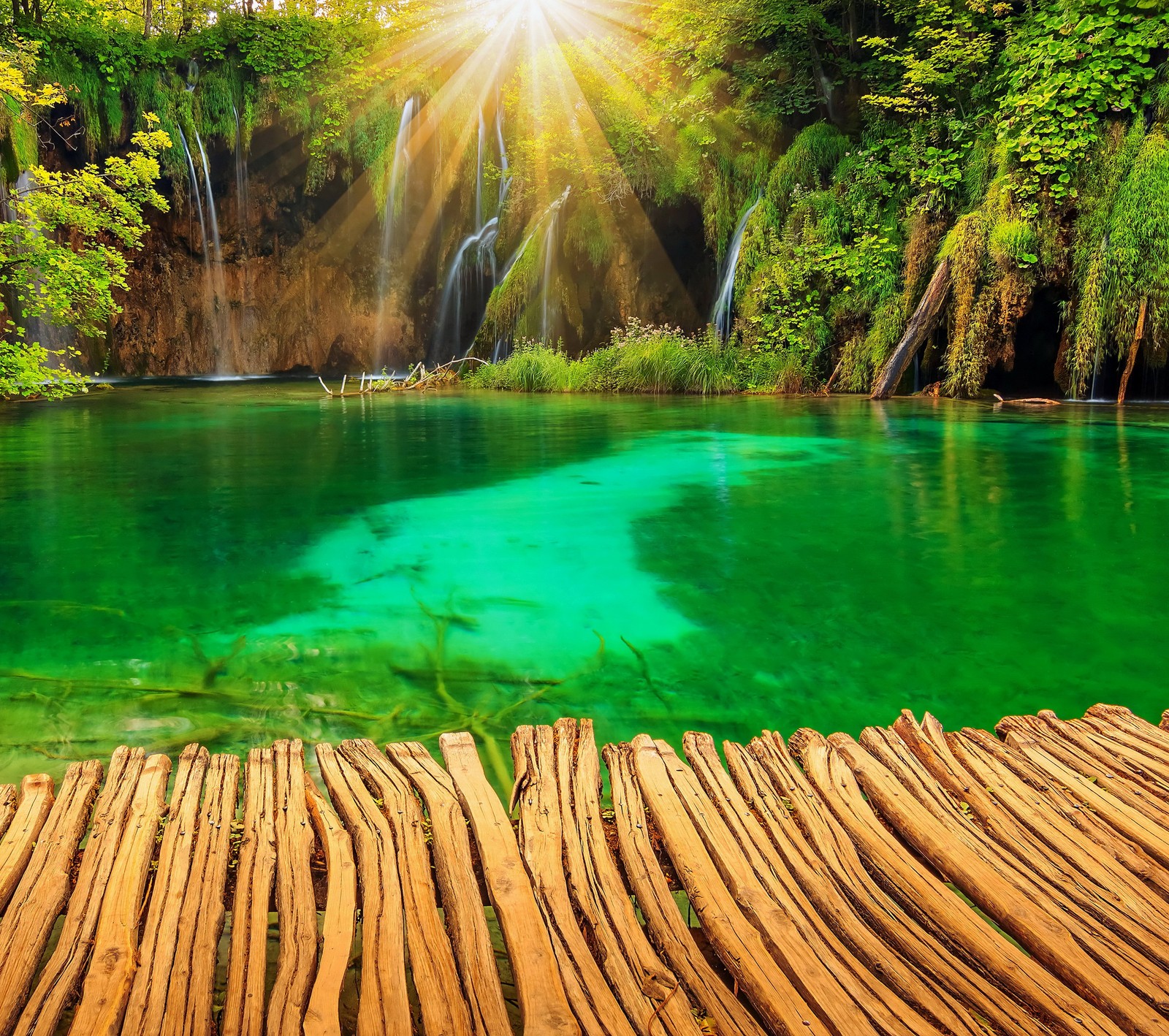 Un quai en bois devant une cascade avec de l'eau verte (croatie, jardin, lac, nature, parcs)