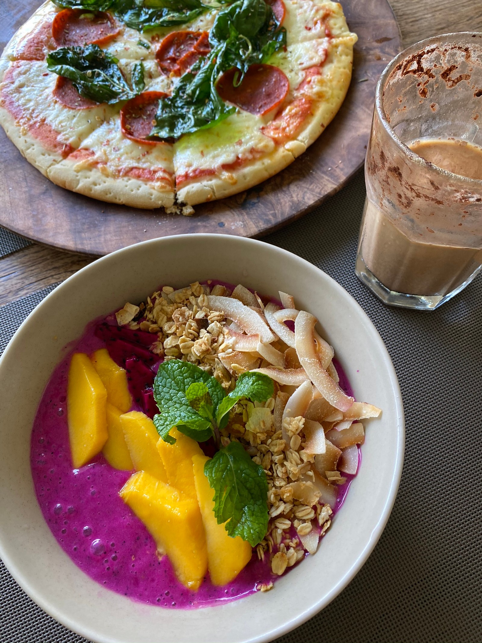 Hay un tazón de frutas y una pizza sobre la mesa (comida, desayuno, cocina vegetariana, plato lateral, cocina)