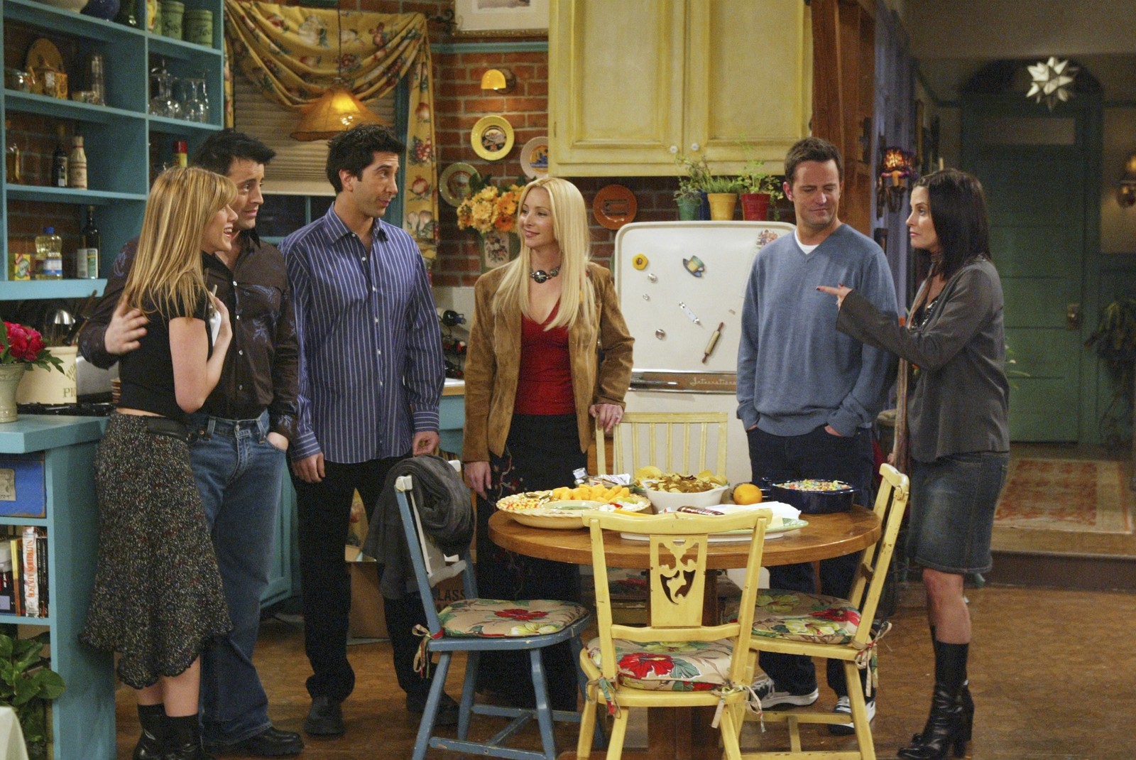 Araffes are standing around a table in a kitchen with a refrigerator (friends, rachel green, monica geller, chandler bing, ross geller)