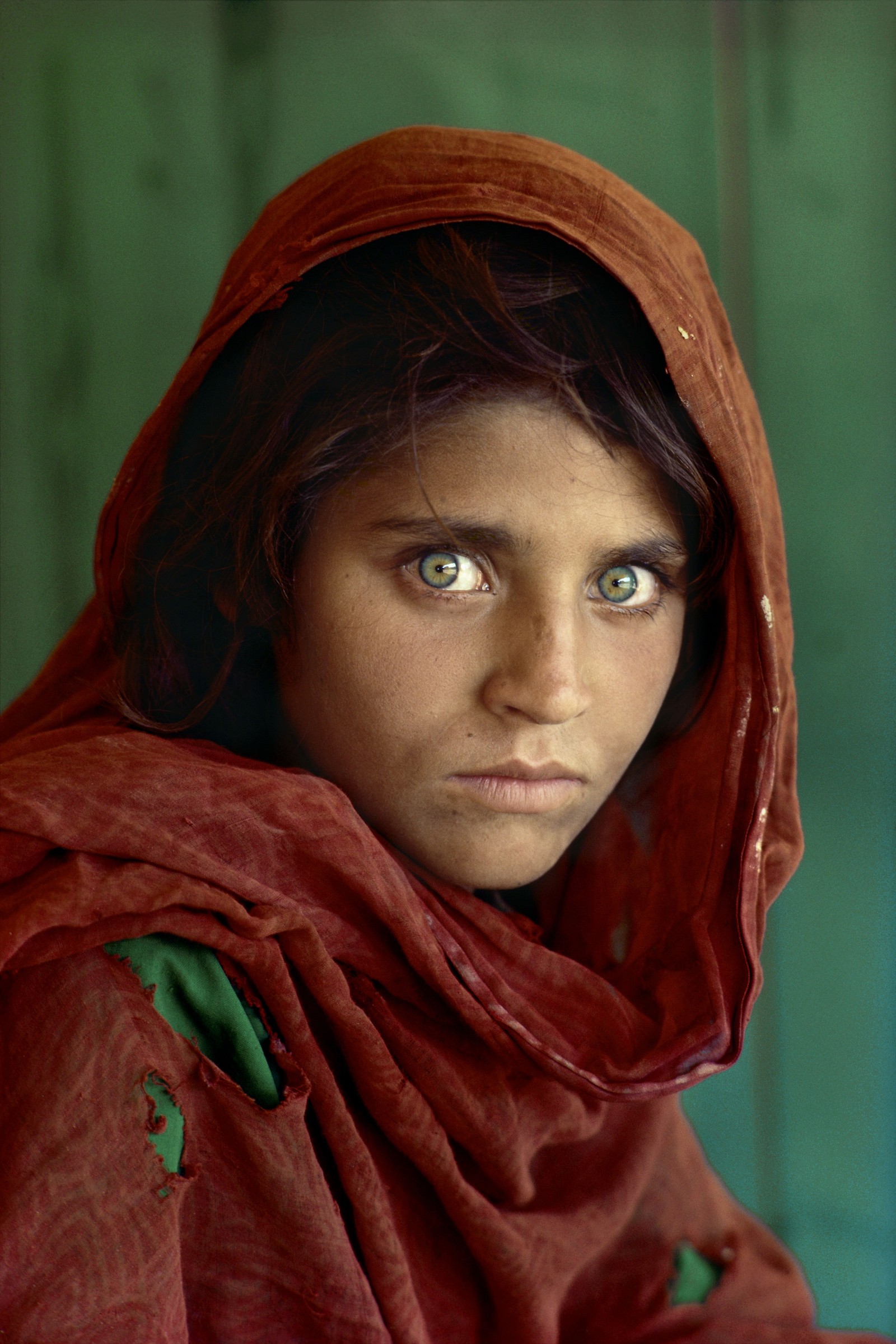 Une femme avec une écharpe rouge et des yeux verts devant un mur vert (afghanistan, national geographic, visage, œil, front)