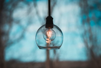 Élégant lustre en verre avec ampoule à incandescence contre un ciel bleu