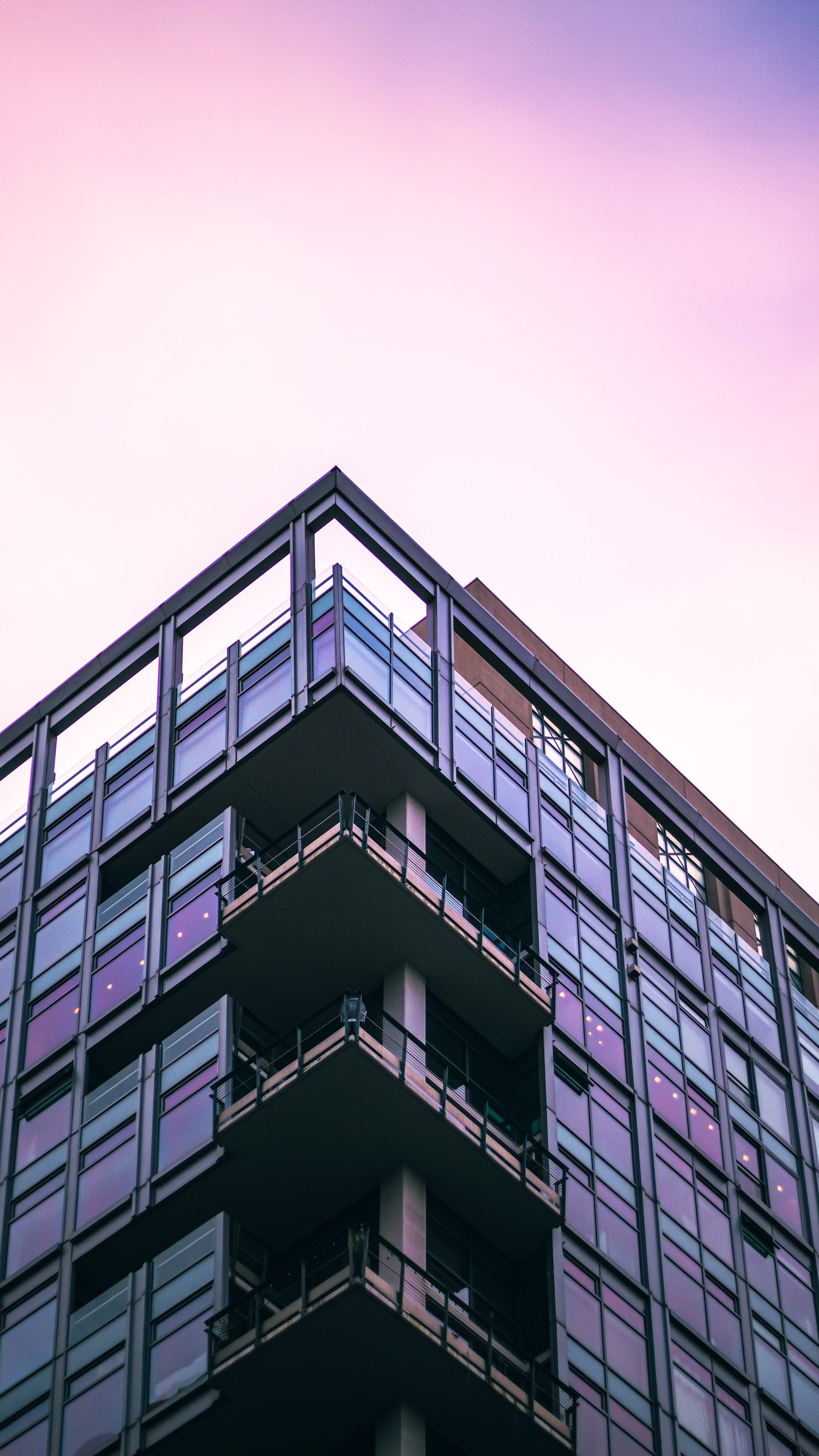 Vista de cima de um prédio com varandas e um relógio no topo (condomínio, arquitetura, edifício, retângulo, roxo)