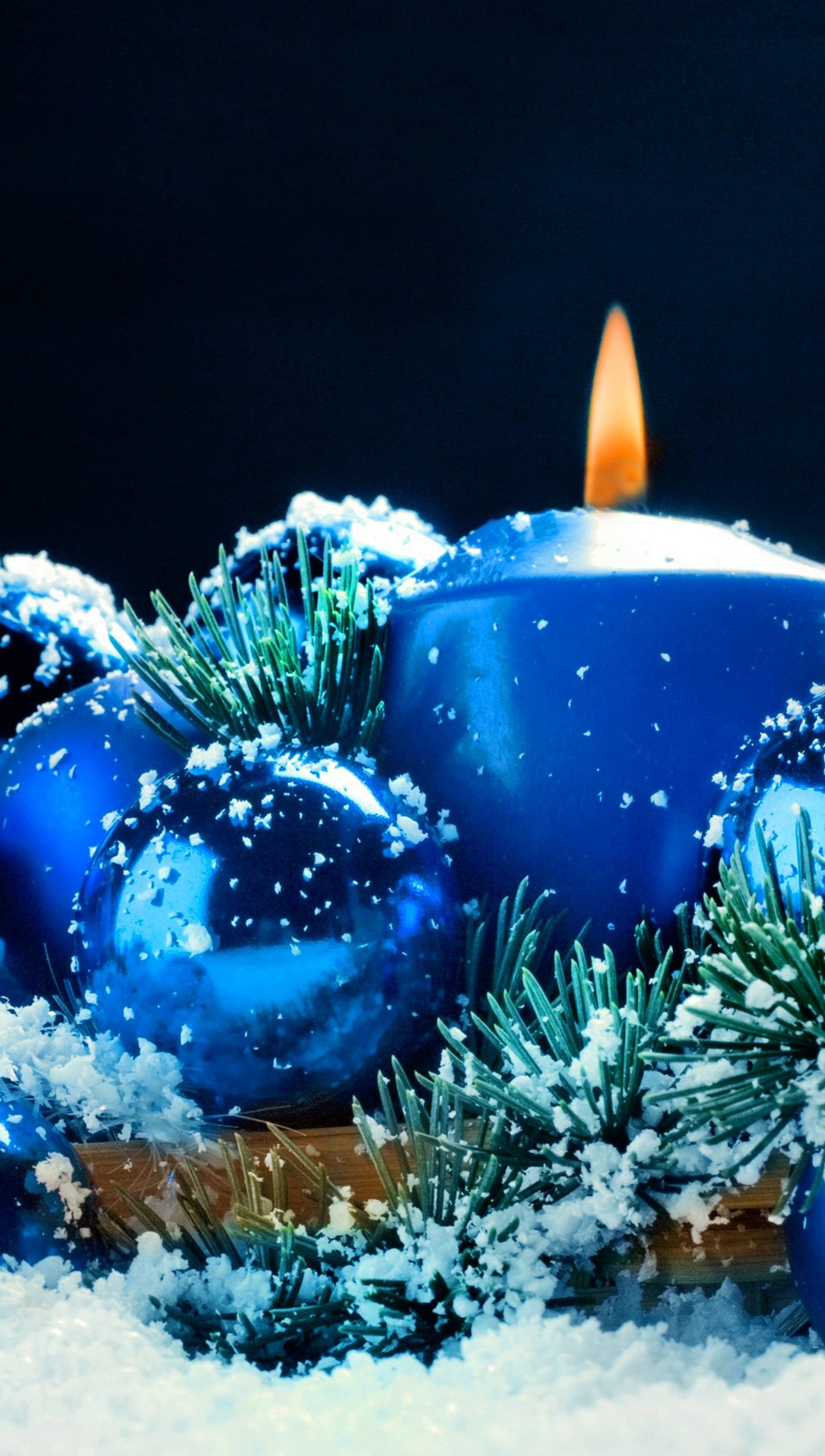 Há uma vela acesa na neve ao lado de algumas decorações de natal (sinos, azul, bulgária, natal)