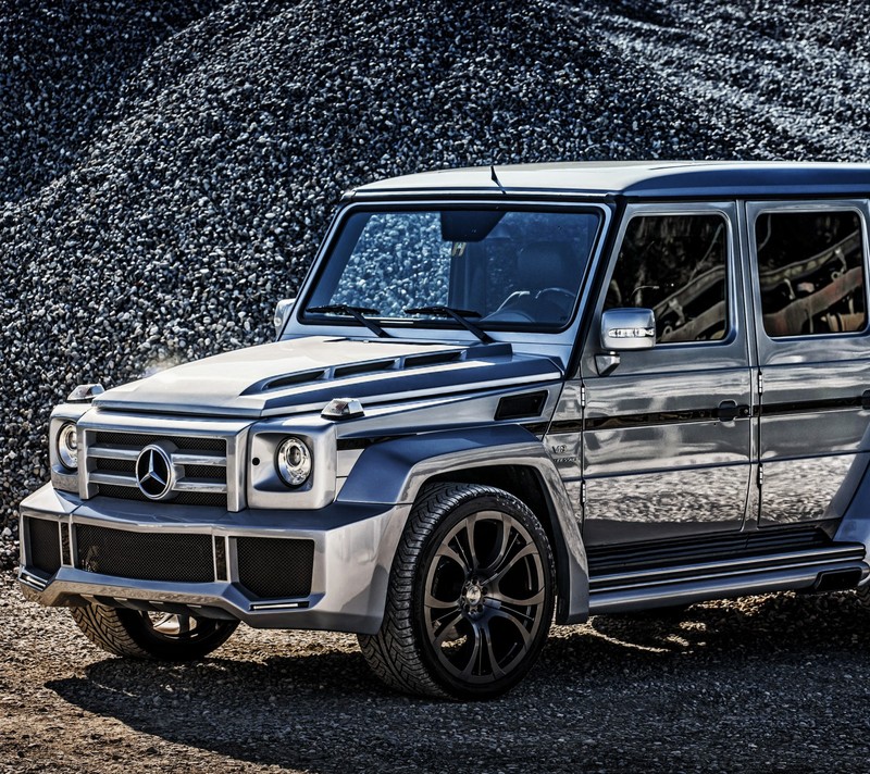 Крупный план серебристого mercedes g-klasse, припаркованного перед кучей камней (benz, g класс, mercedes, w463)