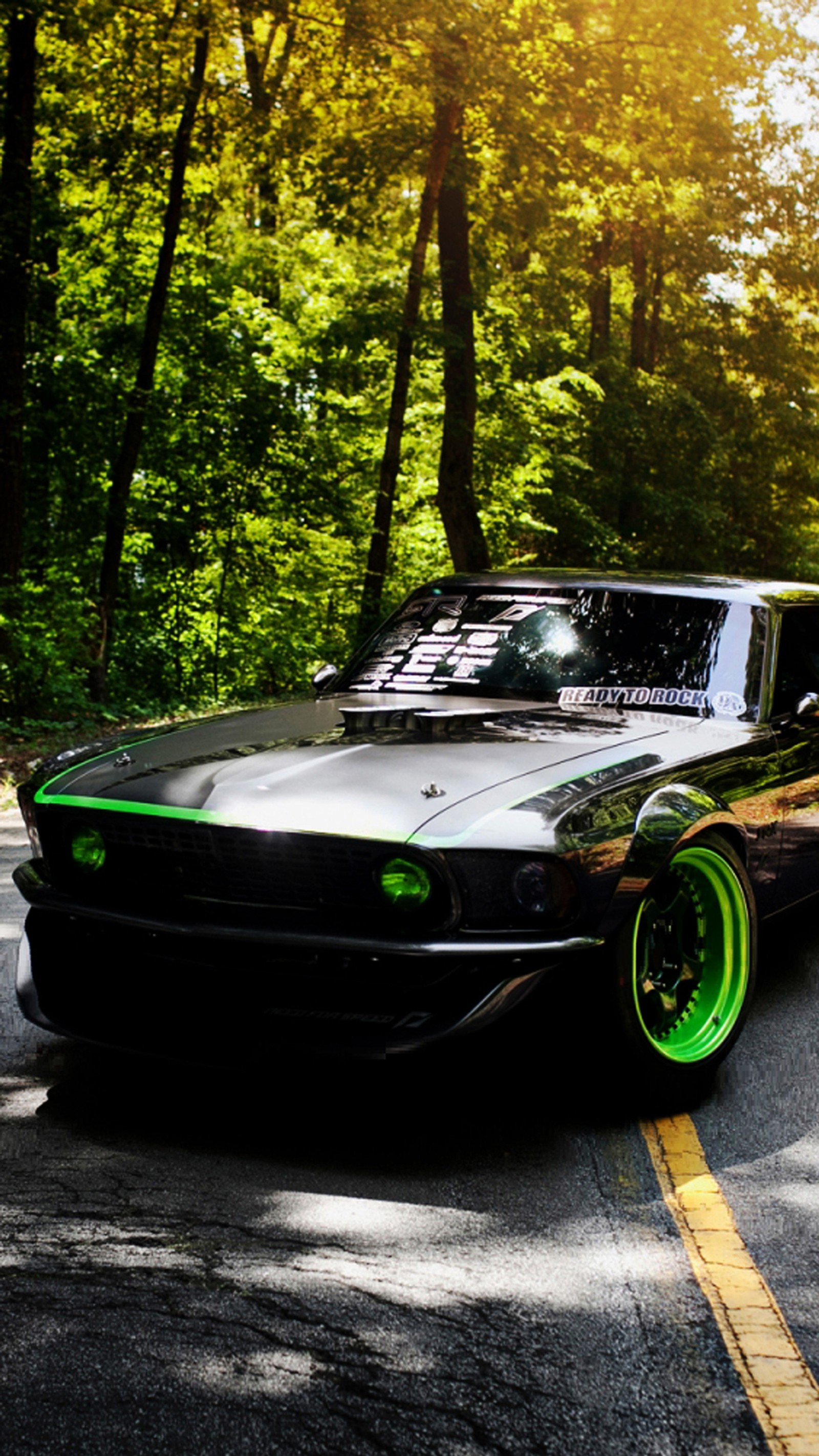 Arafed black car with green rims driving down a road (american, black, car, ford, muscle)