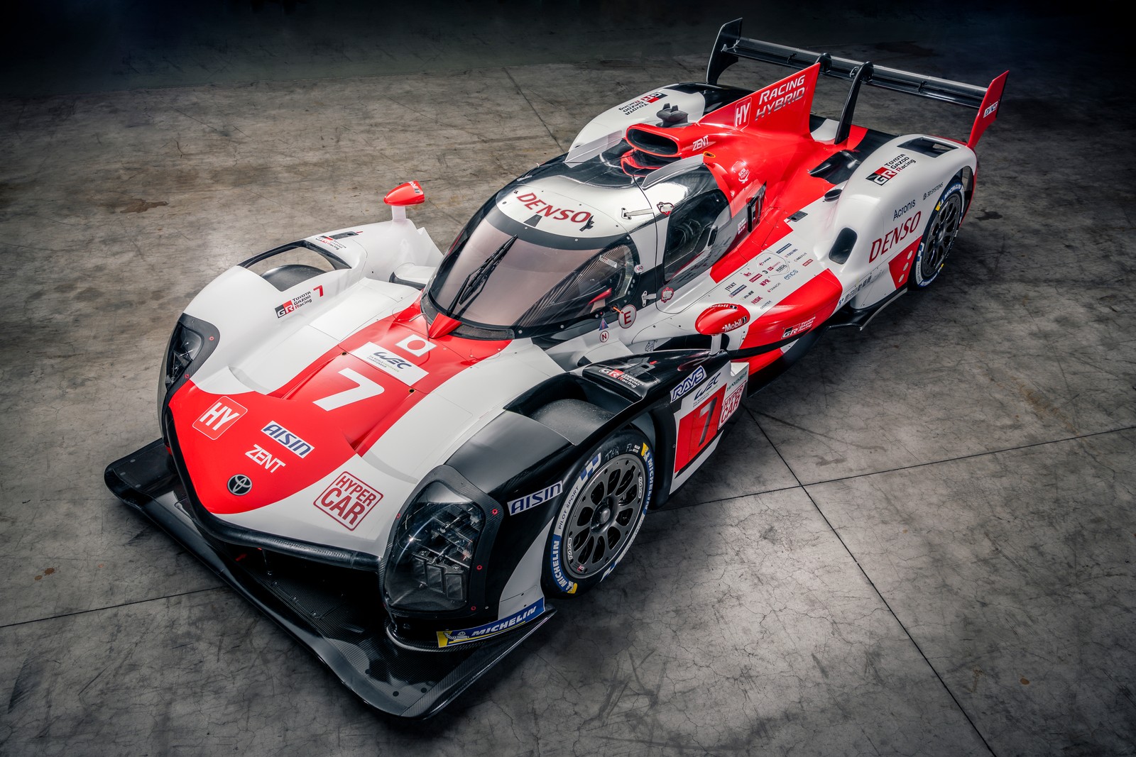 Um carro de corrida vermelho e branco em um piso de concreto (toyota gr010 hybrid, carros esportivos de le mans, hipercarros, 2021, carros de corrida)