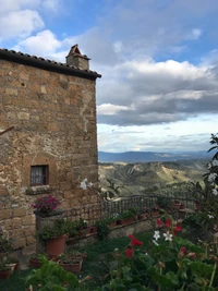 Edificio de piedra histórico con vistas a un paisaje de pueblo montañoso bajo un cielo nublado