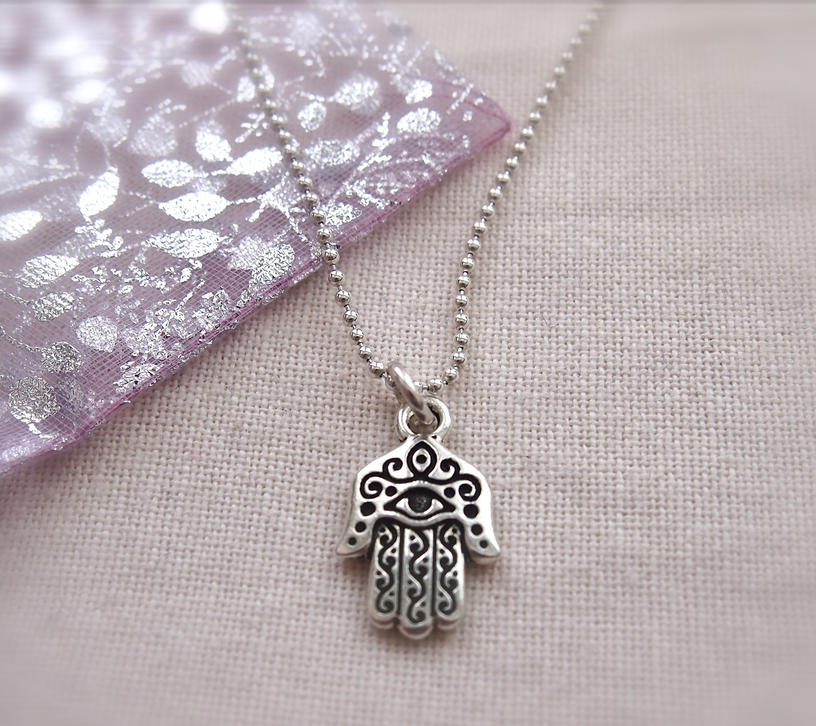 Um close-up de uma mão hamsa em uma corrente sobre uma mesa (buda, buddha, protection, espiritual)