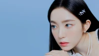 Irene do Red Velvet com um estilo elegante e uma expressão serena contra um fundo azul suave.