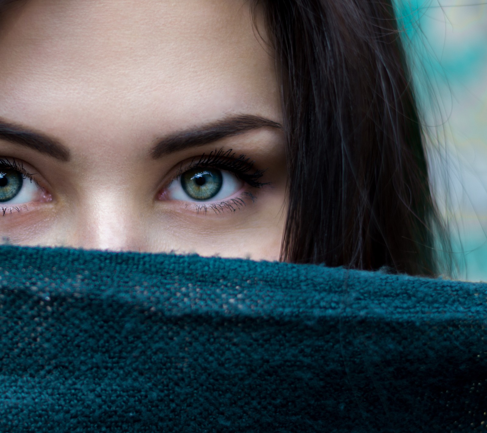 Há uma mulher com um lenço verde cobrindo seu rosto (preto, olho, feminino, menina, verde)