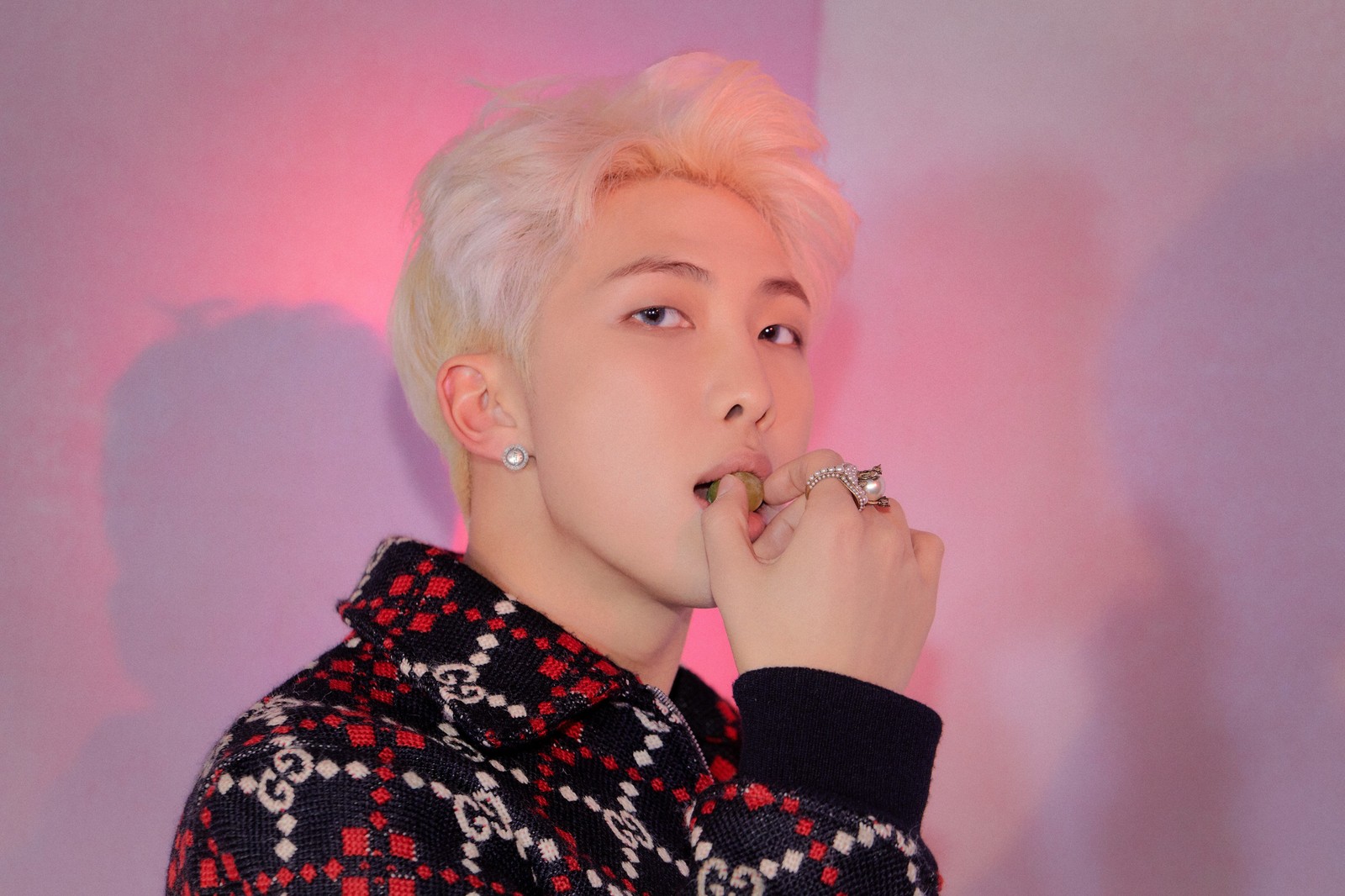 Um homem com cabelo rosa e piercings comendo uma banana (bts, joonie, kpop)